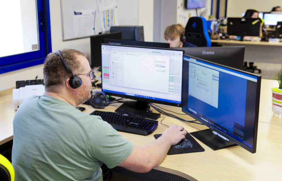 Homme travaillant sur ordinateur avec casques dans bureau.