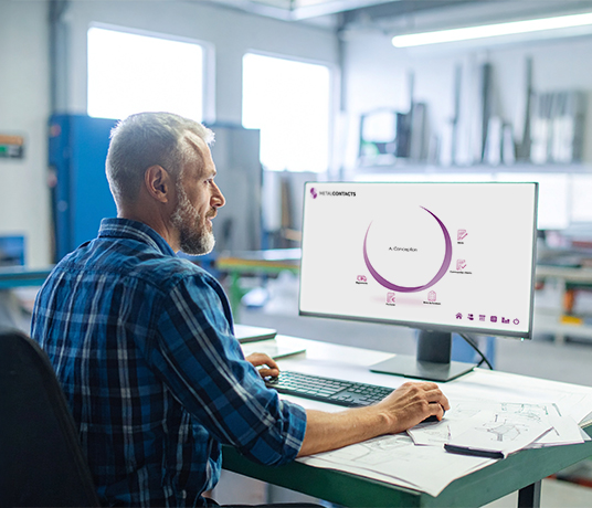 Homme travaillant devant un ordinateur en atelier.