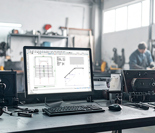 Atelier avec ordinateur et plans techniques.